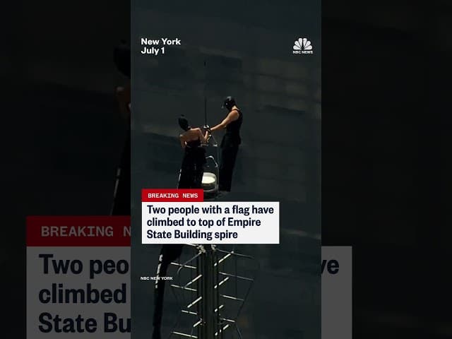 Two people climb the Empire State Building spire